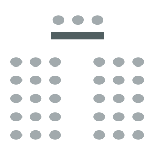 Rows of chairs with a center aisle. Table and chairs for speakers in front facing the room.