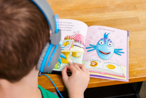 Boy with headphones on looking in a picture book