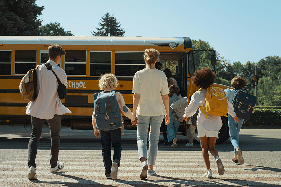 Woman escorting a group of children to a school bus