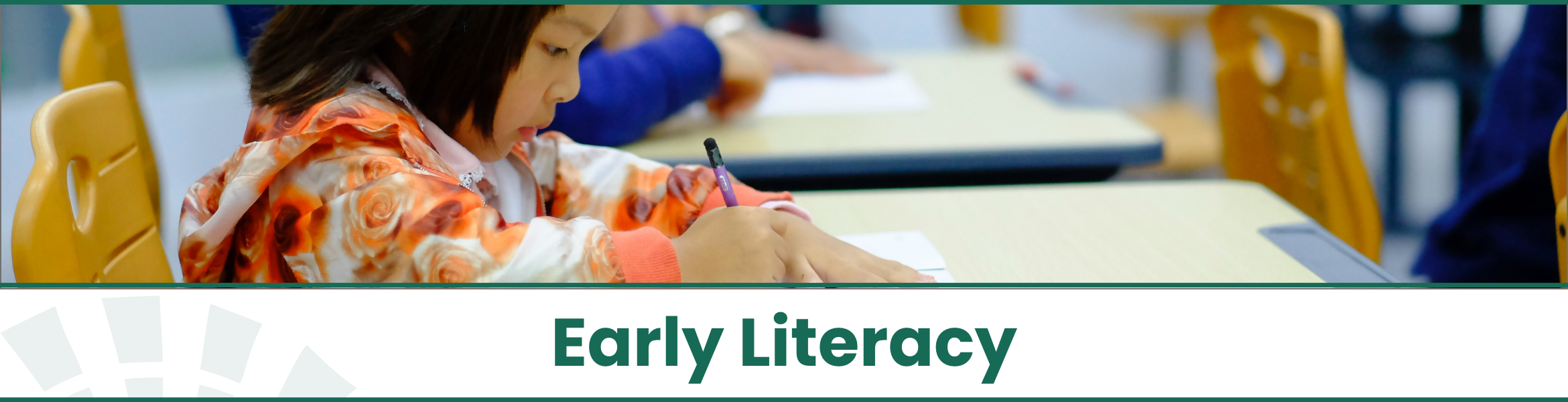 Young toddler girl sitting at a table and writing