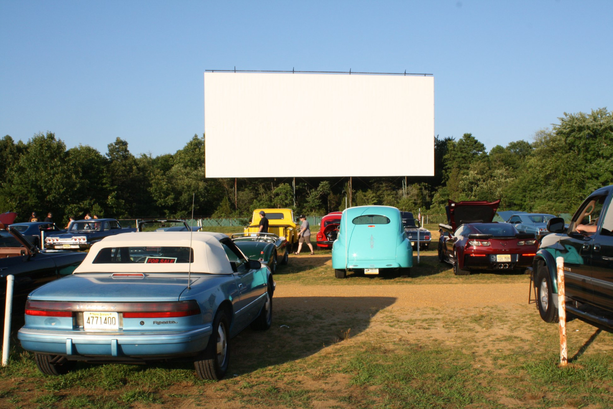 Cars parked in front of a movie screen. 